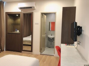 A hotel room with a bed, a TV, a bathroom with a sink, and a shower.