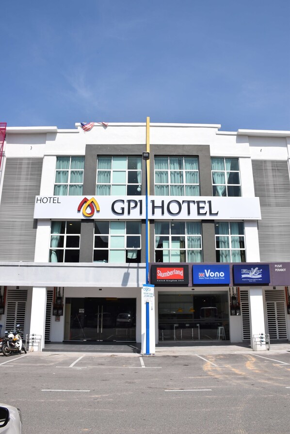 A hotel with a prominent sign reading "GPI HOTEL" and several business names displayed below.