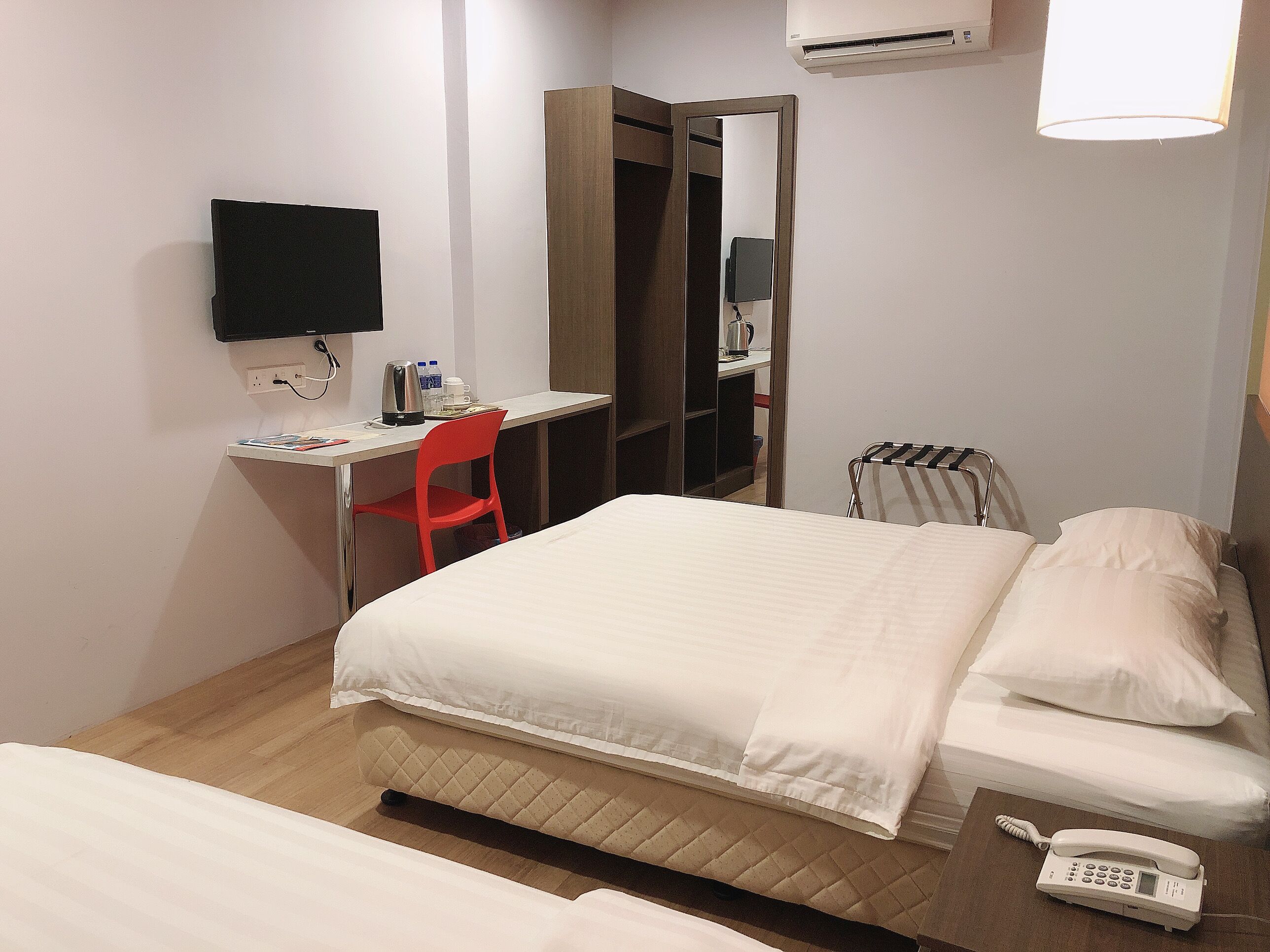 A hotel room with a bed, a desk with a chair, a television, and a telephone.