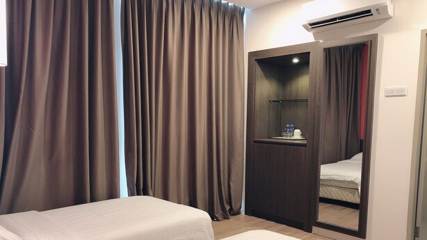 Habitación de hotel con dos camas, un armario, un espejo y un equipo de aire acondicionado.