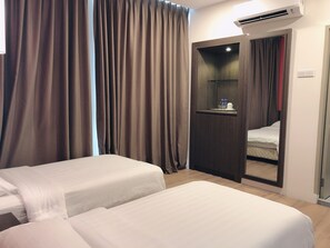 Habitación de hotel con dos camas, un armario, un espejo y un equipo de aire acondicionado.