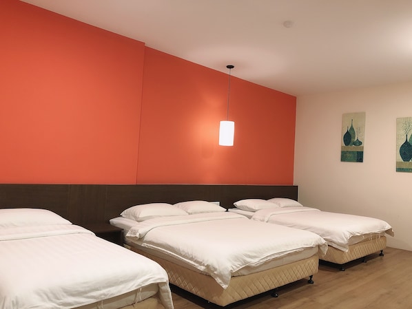 A hotel room with three beds, a large orange accent wall, and a hanging pendant light. - GPI Hotel Bentong (Bentong)