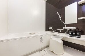 Une salle de bain moderne avec une baignoire blanche, un grand miroir et trois bouteilles de shampoing posées sur le comptoir.