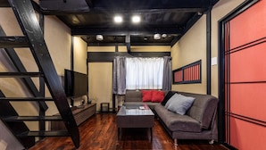 A modern living room with a wooden floor, a sofa, a coffee table, and a TV. - Shiki Homes NATSU (Kyoto)