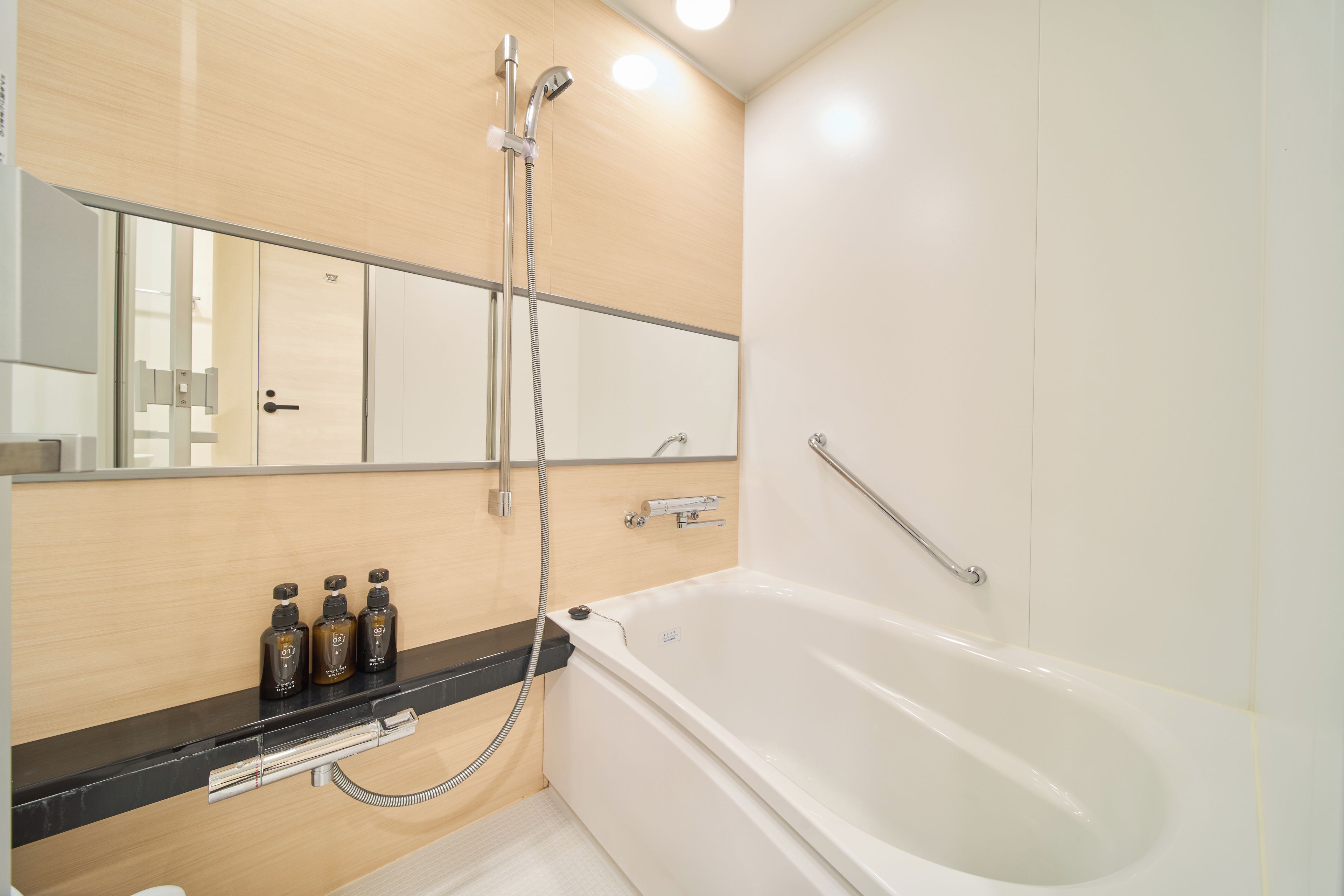 Un baño moderno con bañera, ducha y tocador con tres botellas de champú.
