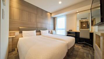 A hotel room with two beds, a desk, a chair, a mirror, and a window.