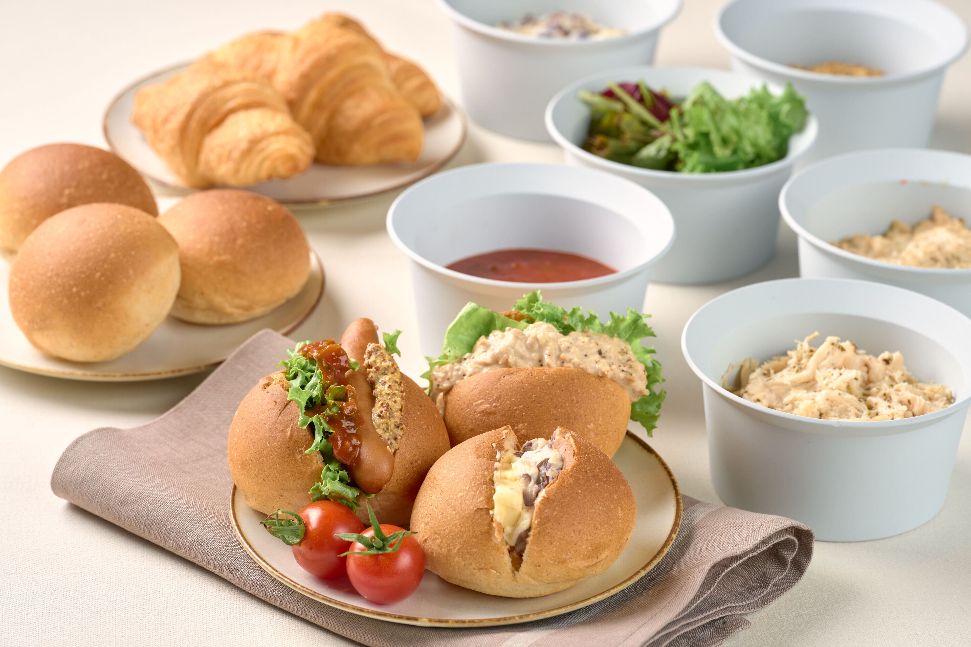 Een tafel met croissants, belegde broodjes en saladekommen.