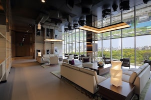 A modern hotel lobby with a seating area, large windows, and a city view.