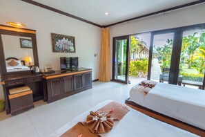 Una habitación de hotel con una cama, un escritorio, un televisor y vistas a un jardín.