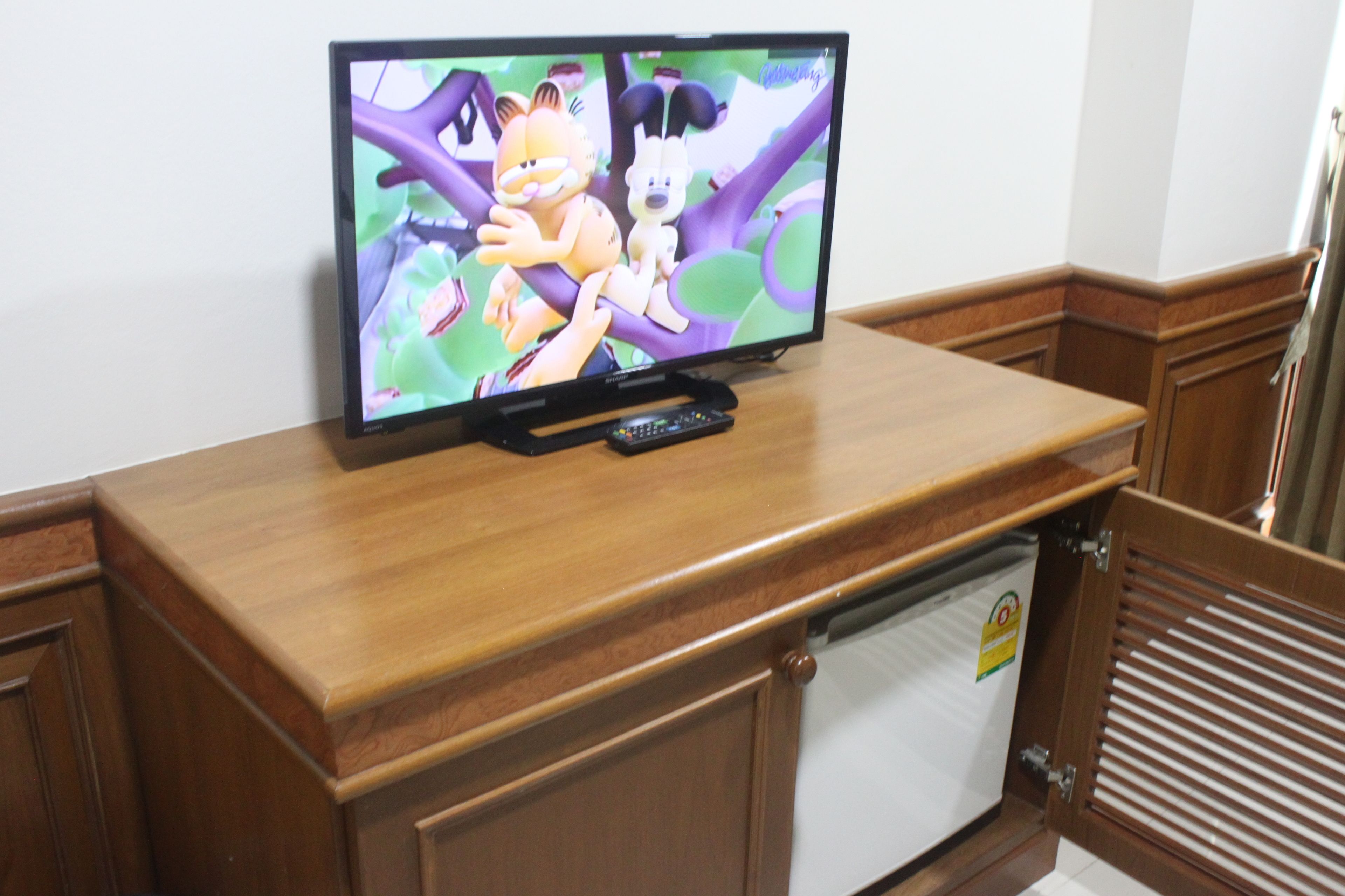 Un televisor sobre un mueble de madera con un control remoto.