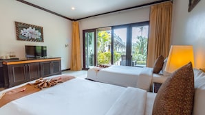 A hotel room with two beds, a television, a desk with a computer, and a large window with a view of greenery.