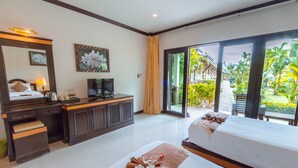 A hotel room with a bed, a desk, a TV, and a view of the garden.