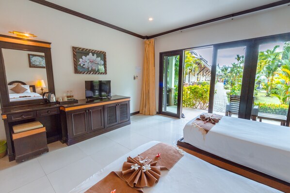 A hotel room with a bed, a desk, a TV, and a view of the garden. - Airport Resort Phuket (Sa Khu)