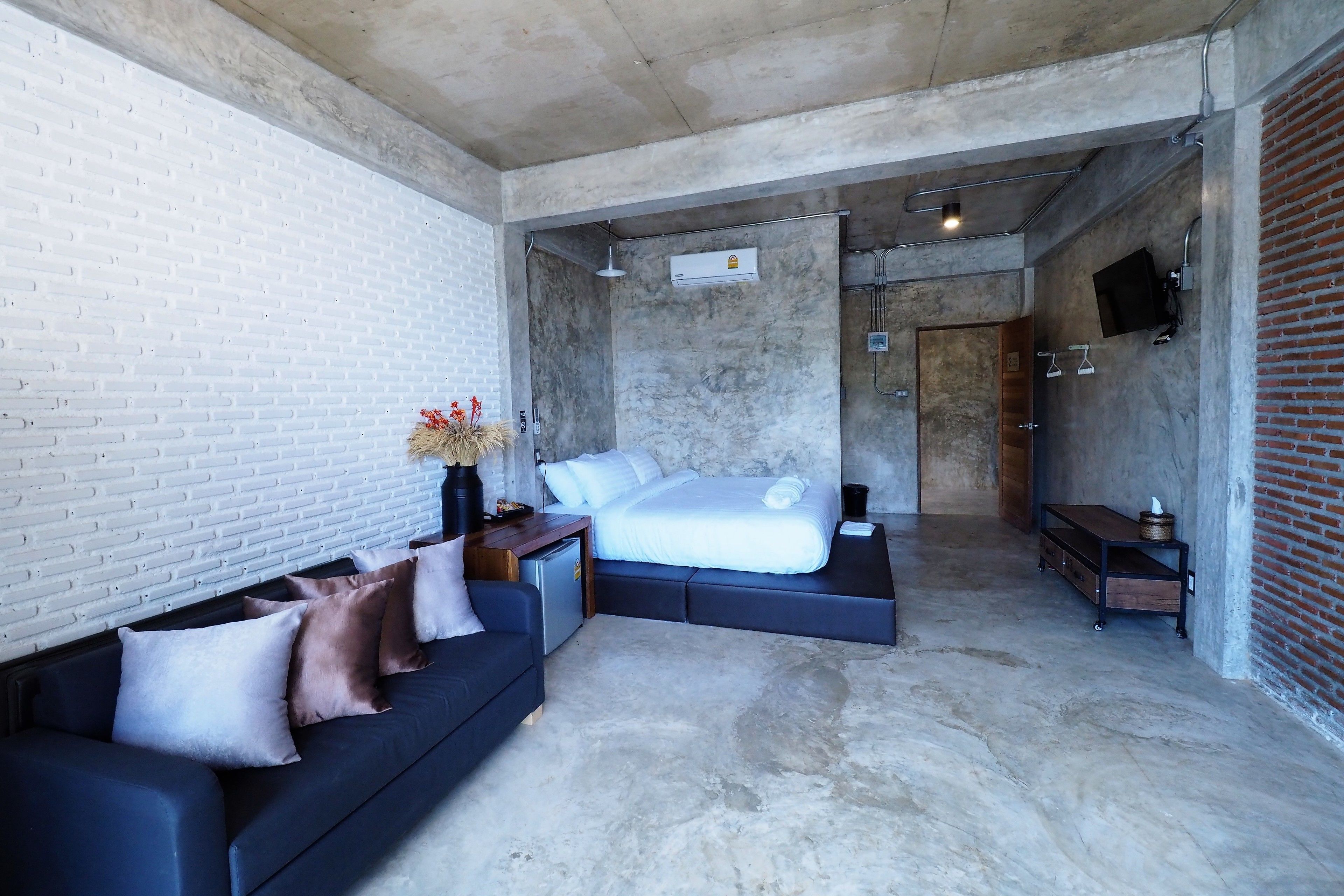 Un dormitorio moderno con una cama grande, un sofá y un escritorio pequeño.
