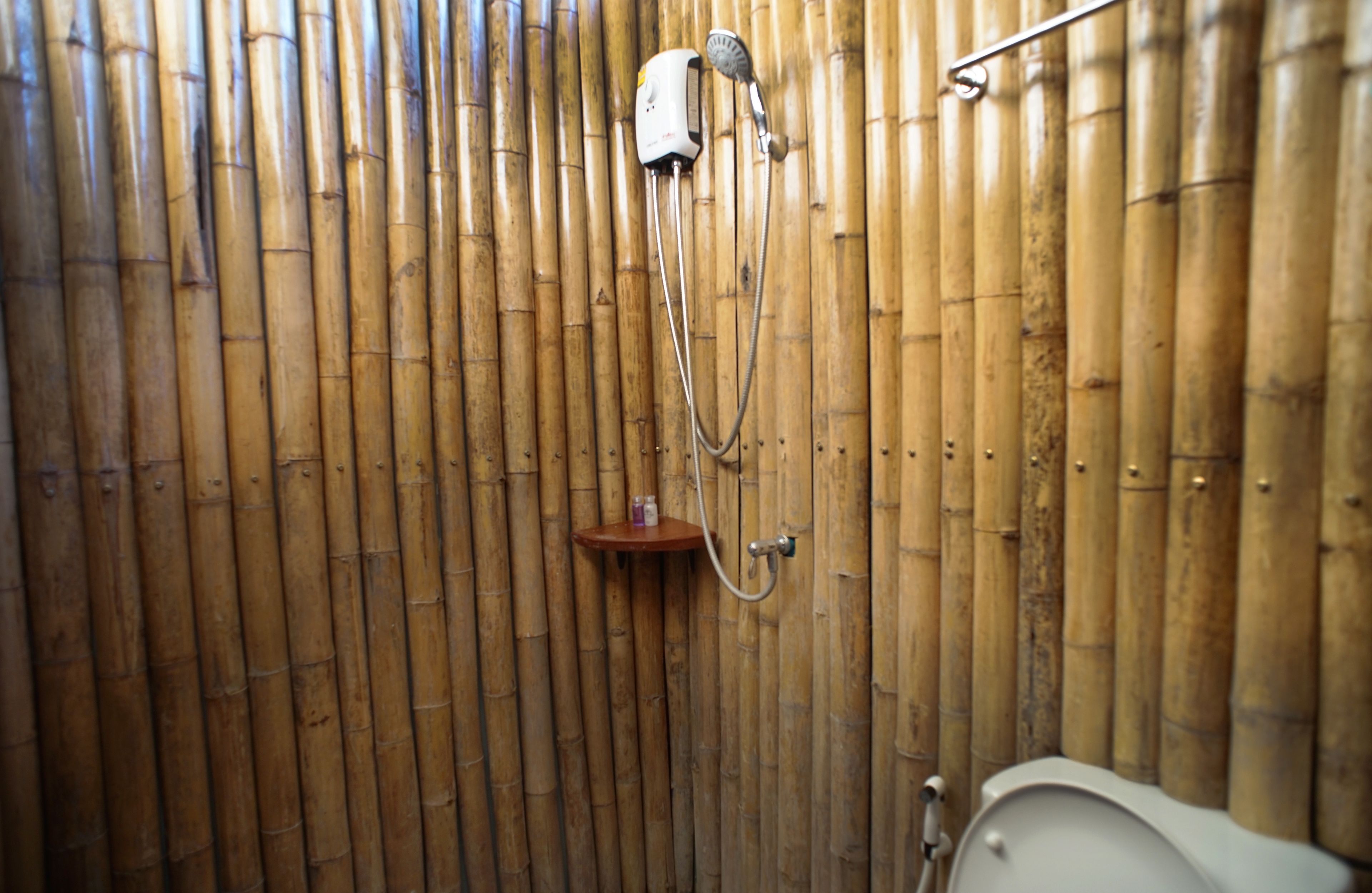 Ducha de bambú con cabezal de ducha y dispensador de jabón manuales.