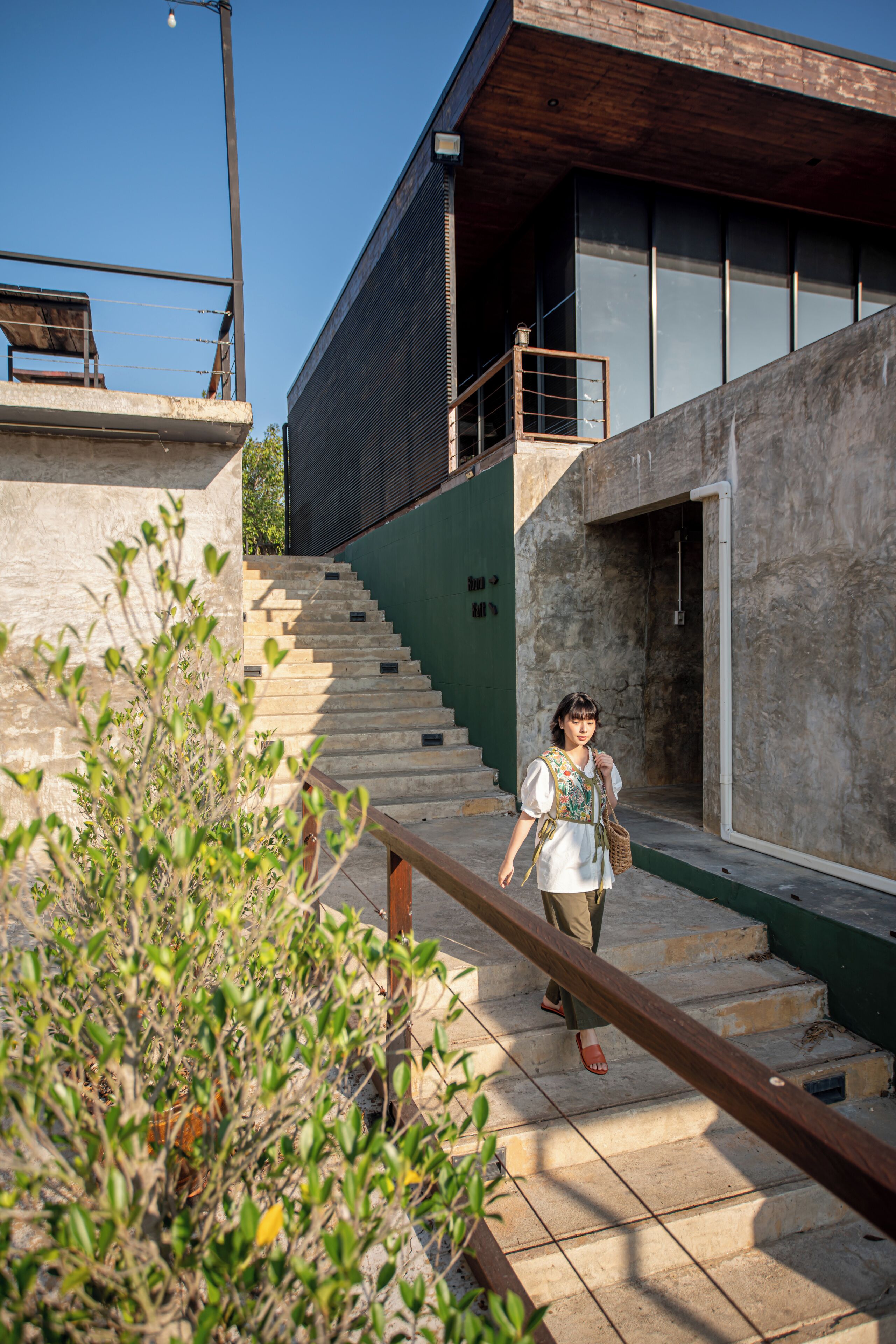 A staircase leading to a modern building with a wooden handrail.