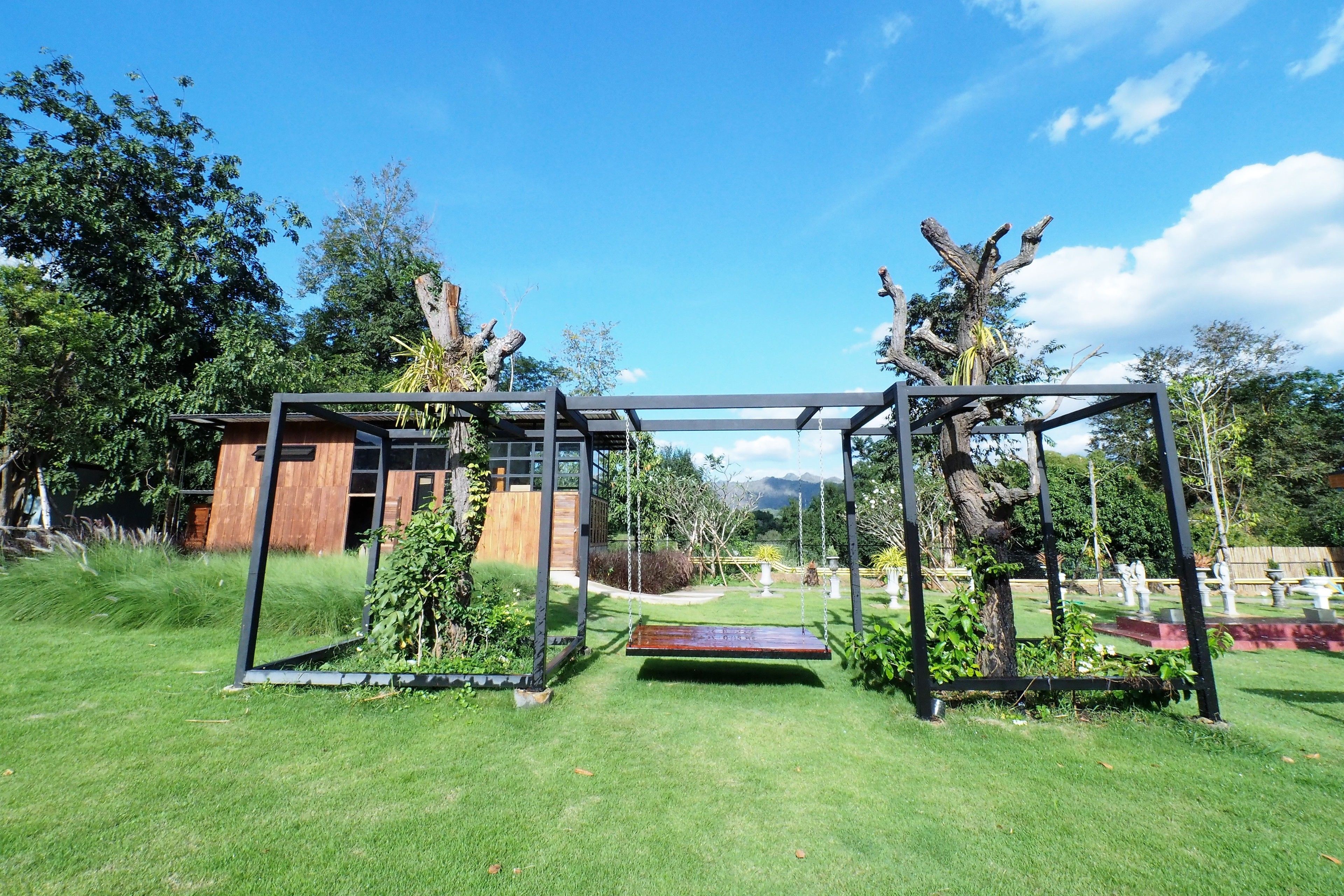 A modern outdoor area with a swing set, a wooden structure, and a well-maintained lawn.