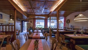 A restaurant with wooden tables and chairs, a checkered tablecloth, and hanging lamps. - Berggasthof & Hotel Hinterrod (Eisfeld)