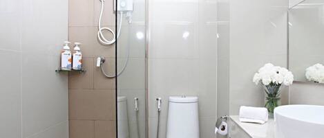 A modern bathroom with a glass shower enclosure, a toilet, and a sink with a mirror.