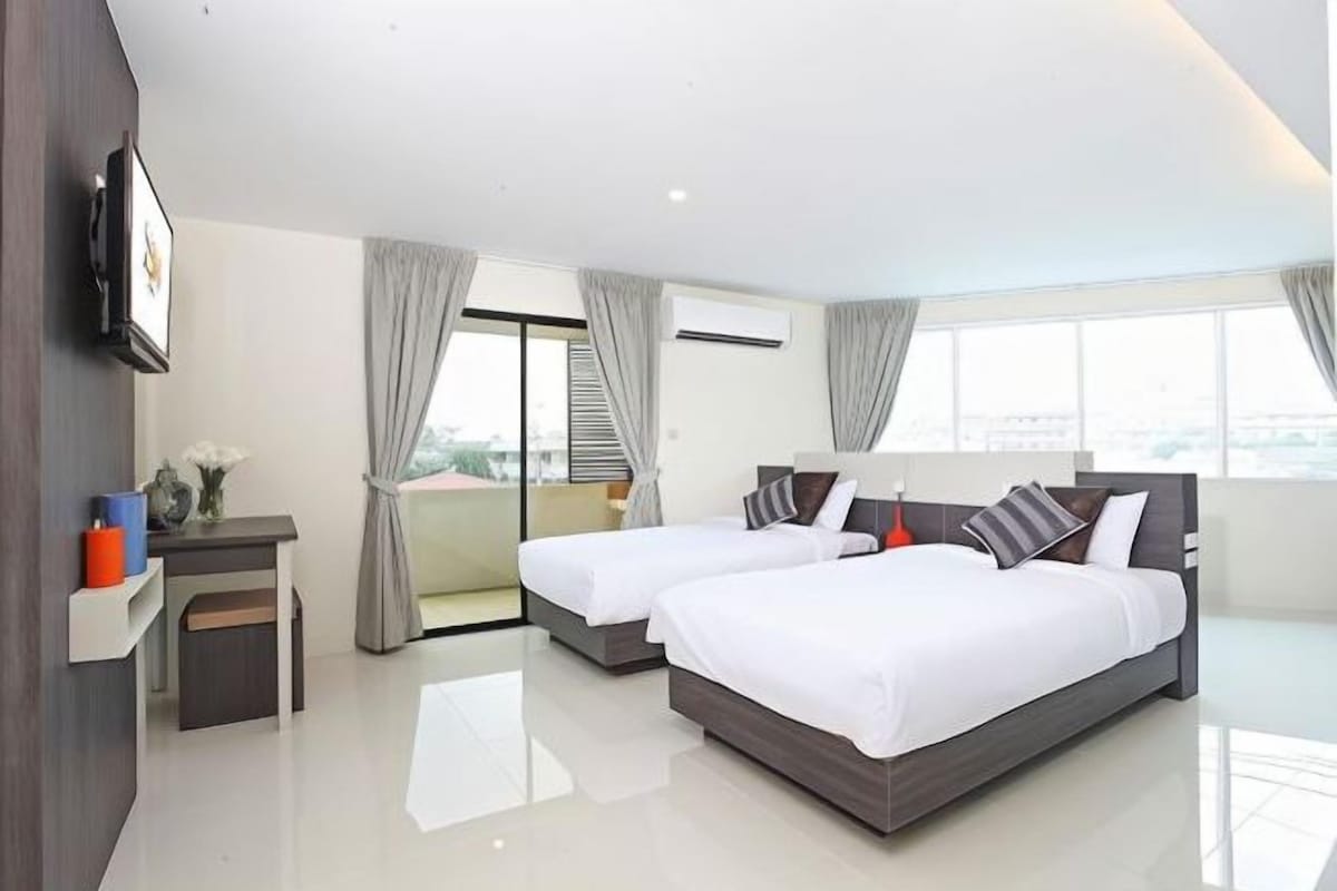 A modern hotel room with two beds, a desk, and a large window with curtains.