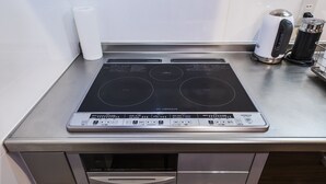 Et køkken med en indbygget induktionskogeplade, kaffemaskine og elkedel.