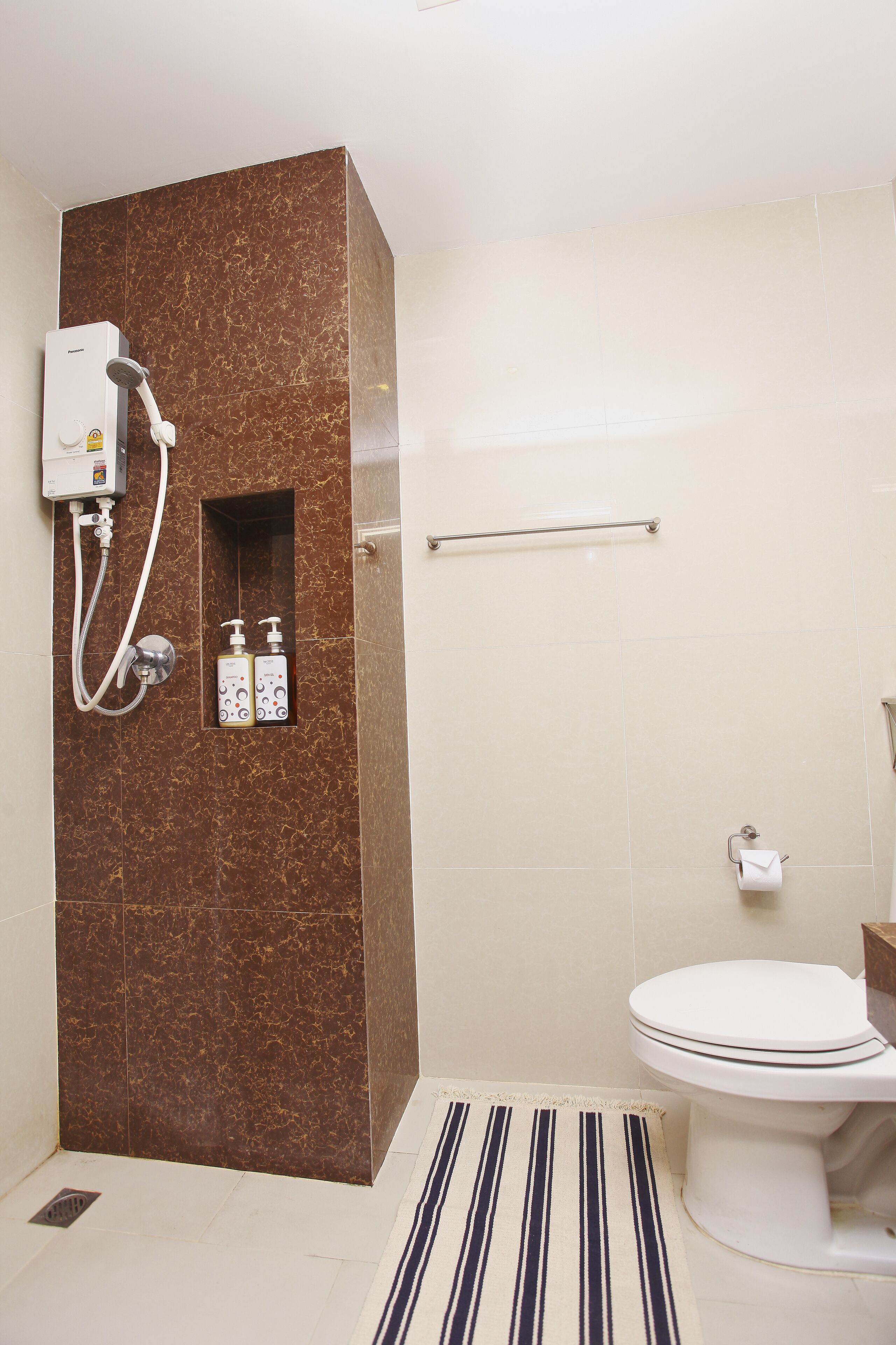 A bathroom with a shower, toilet, and a hand sanitizer dispenser.