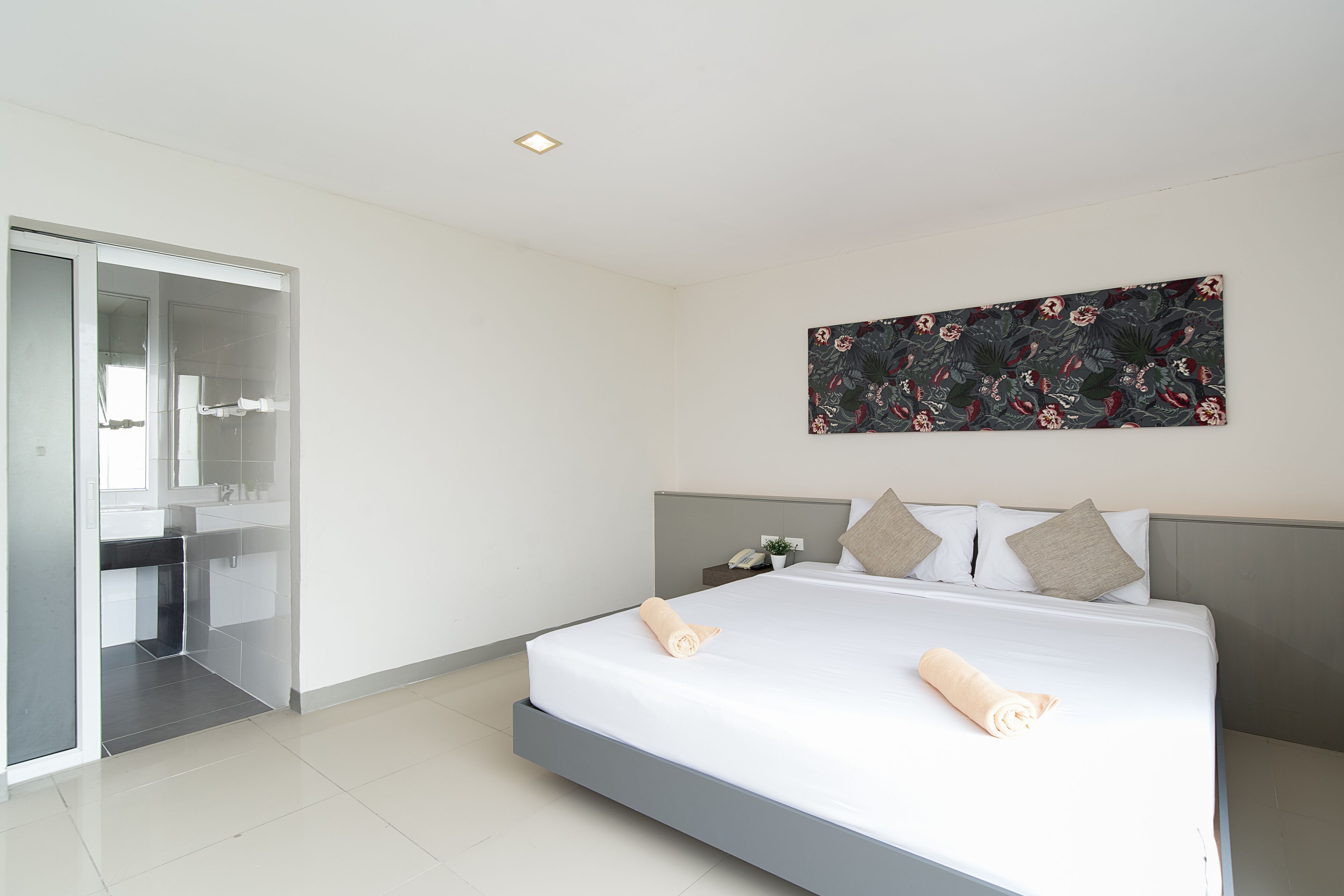 Una habitación de hotel moderna con una cama grande, un box de ducha de vidrio y un adorno de pared decorativo.