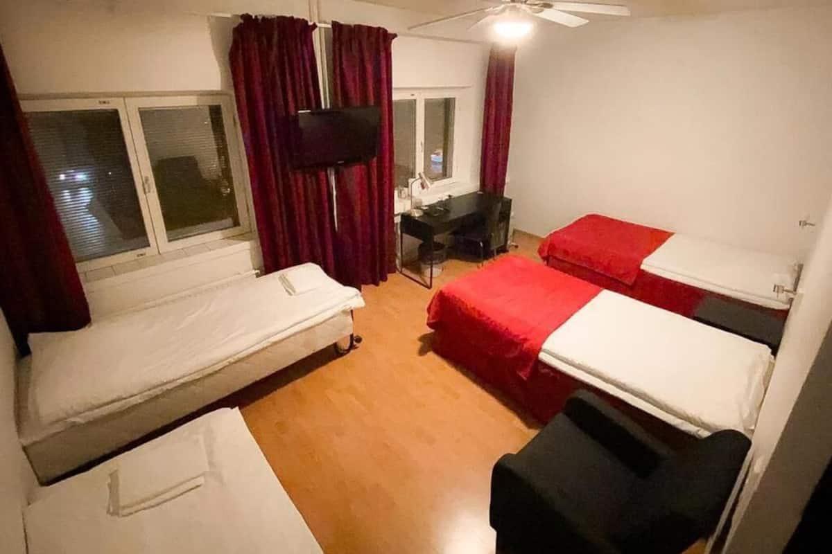 A room with two single beds, a desk, a chair, and a window with curtains.
