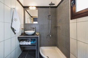 Ein modernes Badezimmer mit Waschbecken, Spiegel, Handtuchhalter und Dusche.