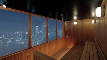 A wooden sauna with large windows offering a city view.