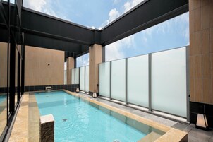 A swimming pool with clear blue water, surrounded by tiled walls and a glass barrier.
