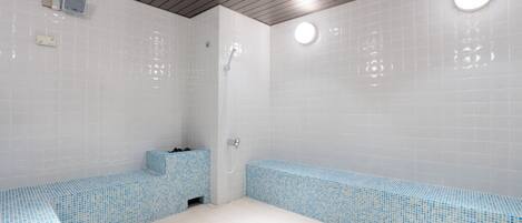 A bathroom with white tiled walls, a wooden ceiling, and a blue mosaic bench.