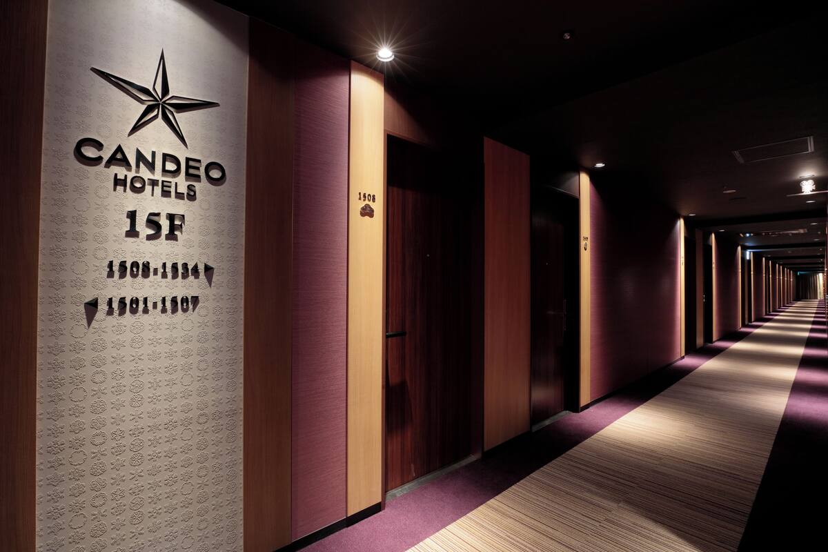 A hallway in a hotel with a star logo and the name "CANDEO HOTELS 15F" on the wall.