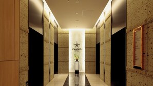 A modern hotel lobby with a polished marble floor, a central reception desk, and a sign for Candeo Hotels. - Candeo Hotels Osaka Namba (Osaka)