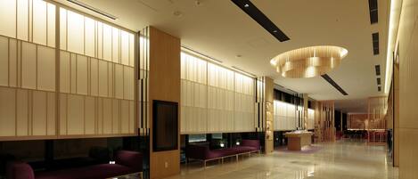 Eine großzügige Lobby mit modernem Design, inklusive einer Rezeption, einer Lounge und einem großen Kronleuchter.