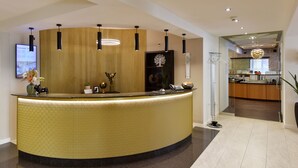 A reception area with a curved counter, pendant lighting, and a modern interior design. - Hotel Engel (Zofingen)