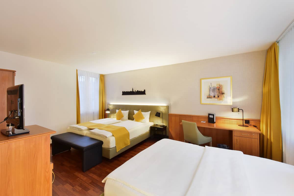 A hotel room with a bed, desk, chair, and a television.