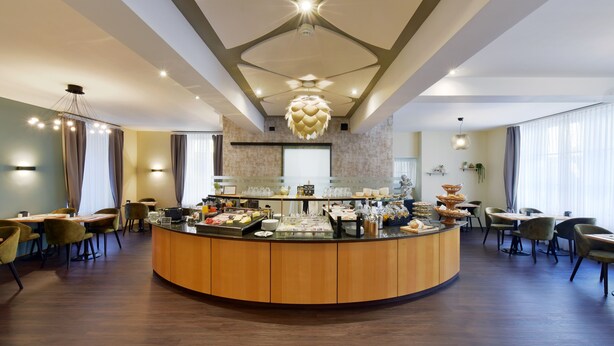 A breakfast bar with various food items, surrounded by seating areas with tables and chairs. - Hotel Engel (Zofingen)