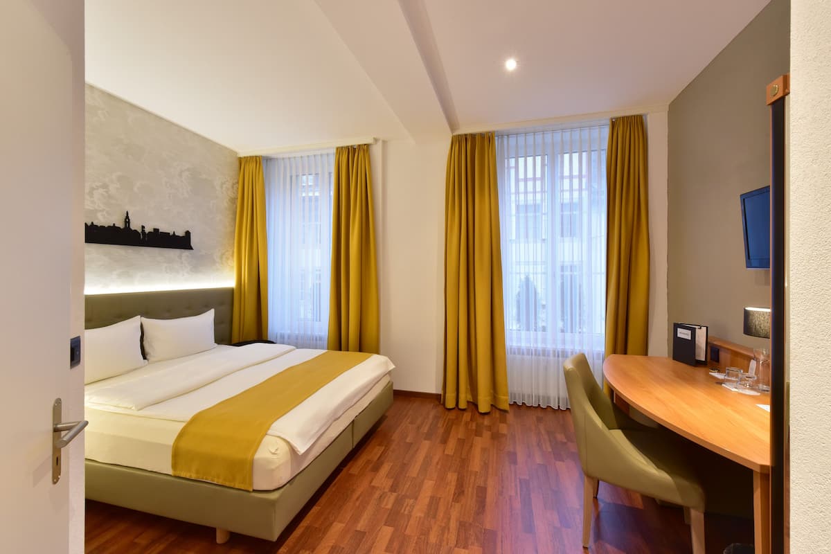 A hotel room with a bed, a desk, and a chair.