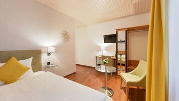 Een hotelkamer met een bed, een bureau, een stoel, een televisie en een spiegel.