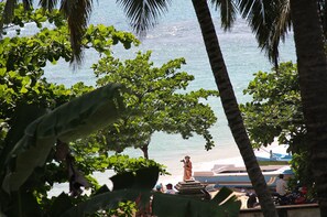 A view of a beach with palm trees and a statue. - Hotel Happy Night & Restaurant (Unawatuna)