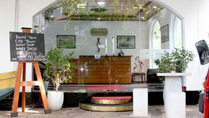 A restaurant with a glass enclosure, a chalkboard menu, and potted plants. - Hotel Happy Night & Restaurant (Unawatuna)