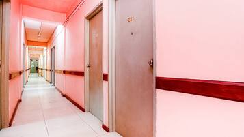 A long corridor with doors numbered 221 and 222, white tiled floors, and a red and white color scheme.