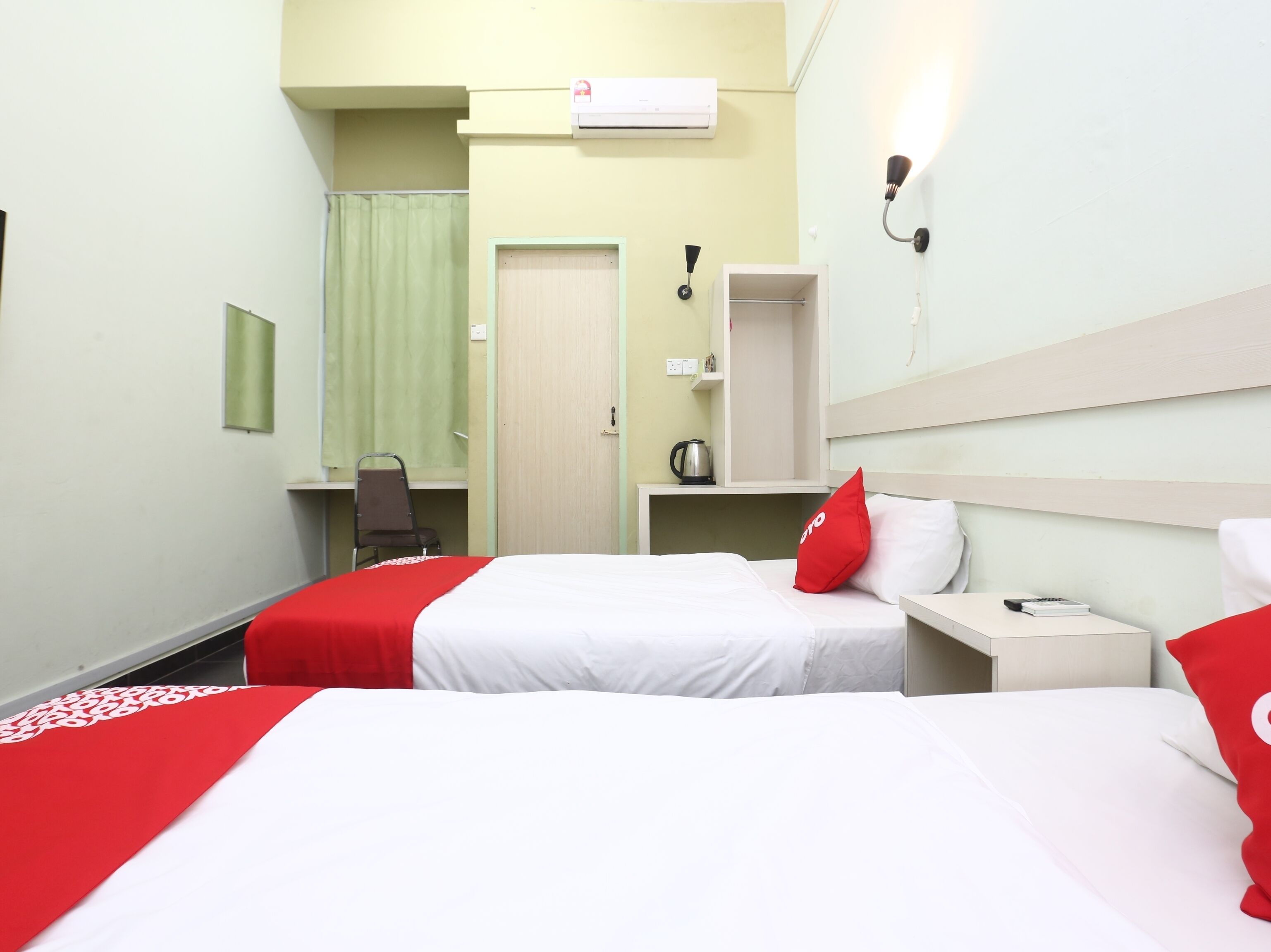 A hotel room with two beds, a desk, a chair, a mirror, and a wardrobe.