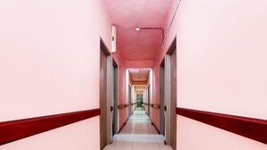 Un long couloir étroit aux murs roses et au sol carrelé de blanc.