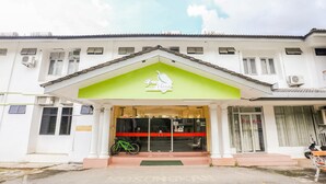 L’entrée d’un hôtel, avec un auvent vert, un vélo garé à l’extérieur et une enseigne indiquant le nom de l’établissement.