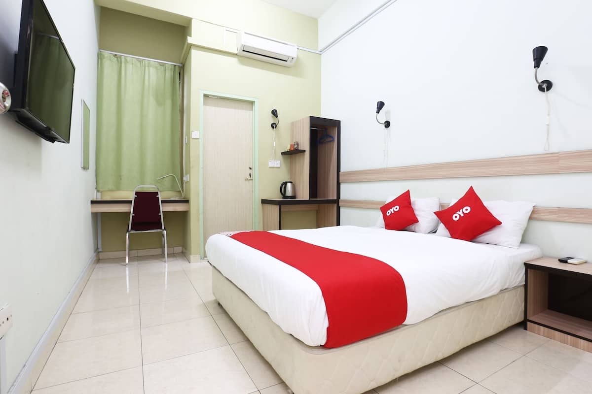 Une chambre d’hôtel équipée d’un lit, d’un bureau, d’une chaise, d’une télévision, d’un climatiseur et d’une table de chevet.
