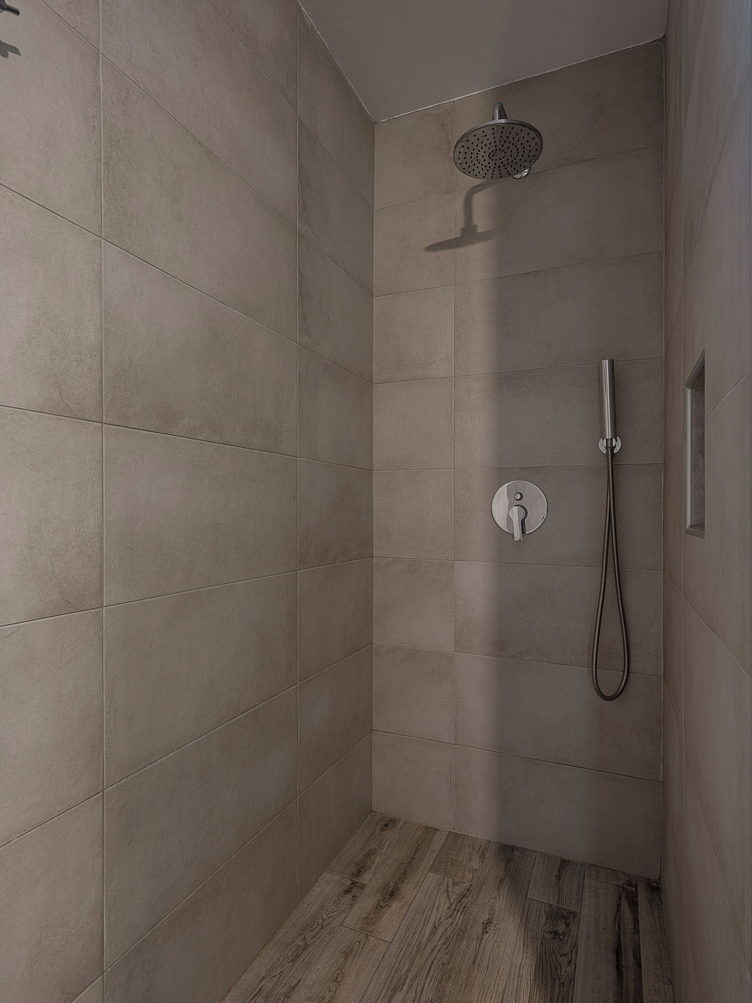 A modern shower with a handheld showerhead and a wall-mounted control panel.