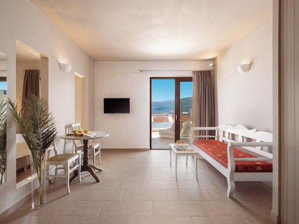 A modern hotel room with a balcony, a dining area, and a seating area. - Porto Kaza (Sitia)
