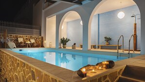 Una piscina con paredes de piedra, techos abovedados y plantas en macetas.